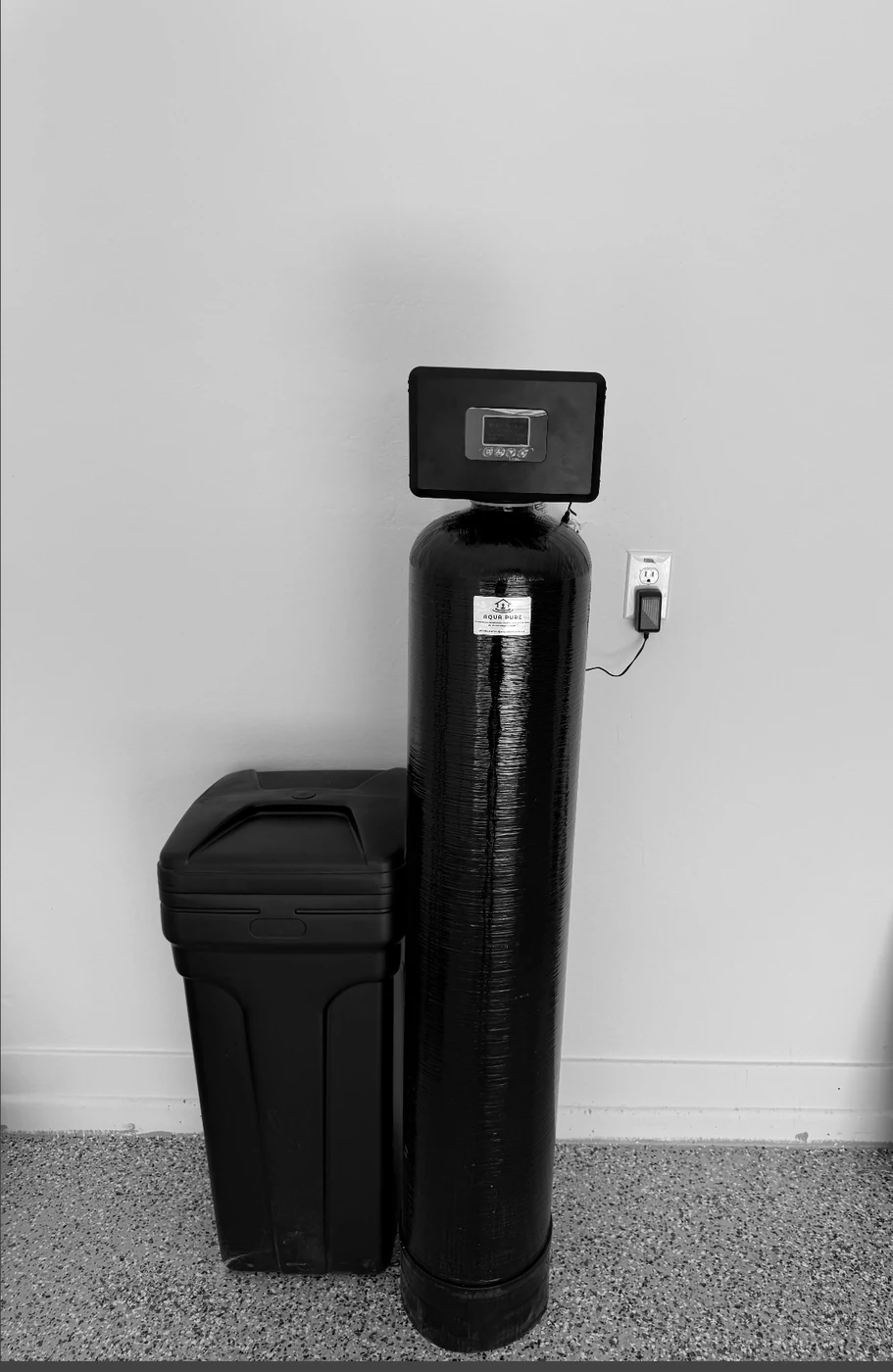 Aqua Pure black whole-home treatment tank and brine tank installed in a garage