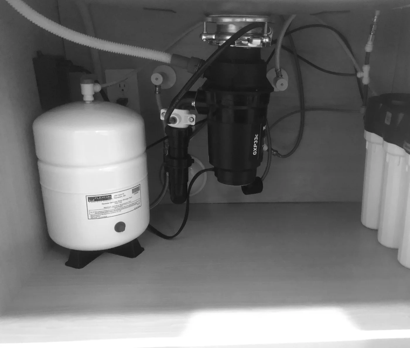 Compact reverse osmosis storage tank and filter housings beneath a sink