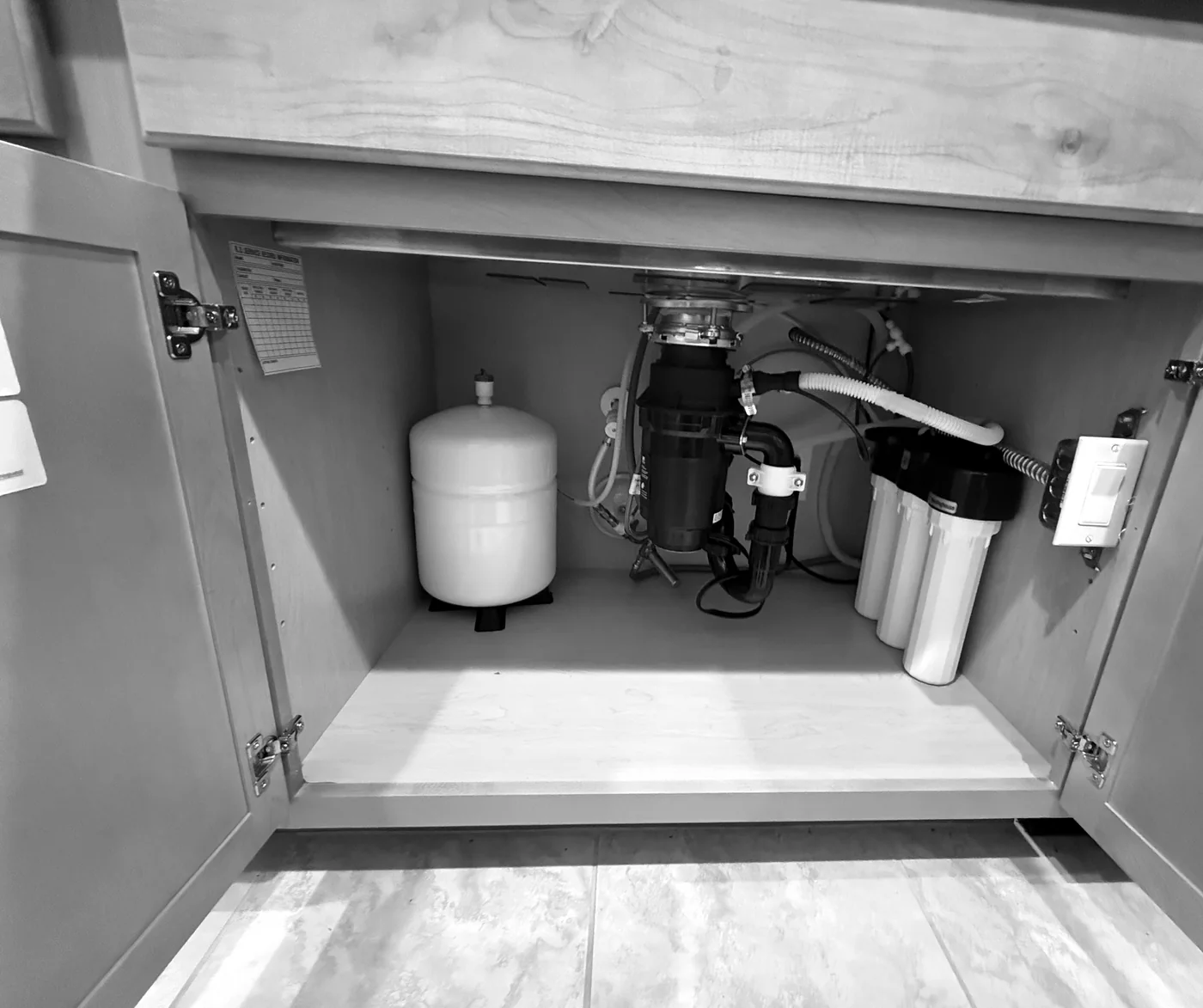 Reverse osmosis storage tank and filter housings installed beneath a kitchen sink